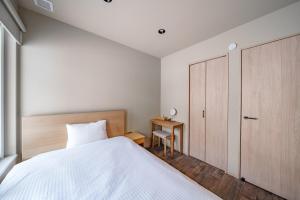 a bedroom with a white bed and a wooden cabinet at ZABOCON Honcho Terrace in Sapporo