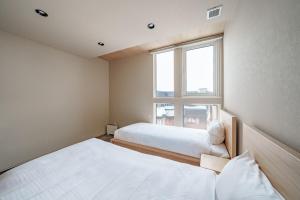 two beds in a small room with a window at ZABOCON Honcho Terrace in Sapporo