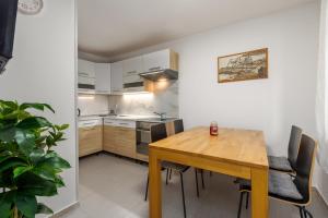a small kitchen with a wooden table and chairs at Apartments Sidro in Savudrija