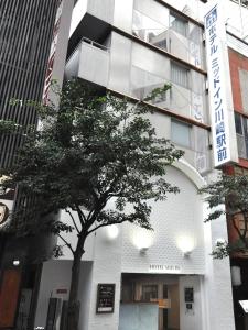 a building with a tree in front of it at Hotel Mid In Kawasaki Ekimae in Kawasaki