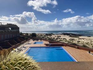 a view of a swimming pool and the beach at Beach Apartment Marfolin 17 El Cotillo Adults Only in El Cotillo