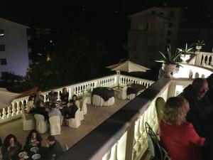 a group of people sitting on a balcony at night at BB Villa Magda in Novafeltria