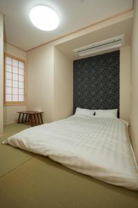a bedroom with a large white bed with a wall at Sumiyoshi Guesthouse 梦阁 粉浜の宿 in Osaka