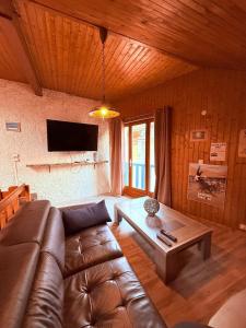 ein Wohnzimmer mit Ledersofa und Couchtisch in der Unterkunft Maison Chamallow in Chorges
