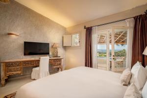 a bedroom with a bed and a television and a window at Petra Segreta Resort & Spa in San Pantaleo +86 photos