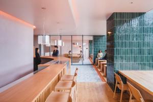 a restaurant with green tiled walls and wooden tables and chairs at THE TSUBAKIMORI Hotel & Residence in Chiba