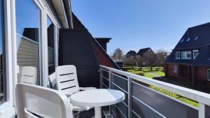 a balcony with white chairs and a table at Strand Sand Sylt in Westerland +6 photos