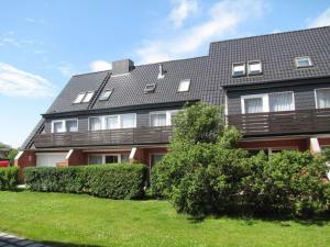a large house with bushes in front of it at Strand Sand Sylt in Westerland