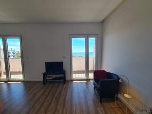 an empty living room with a chair and windows at Bright by the Beach - by CoH in Cruz Quebrada