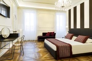 a bedroom with a bed and a couch and a chandelier at Best Western Plus Royal Superga Hotel in Cuneo
