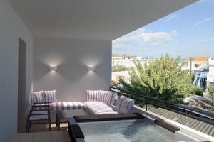 a balcony with two chairs and a swimming pool at Aktaion Signature Suites in Skala
