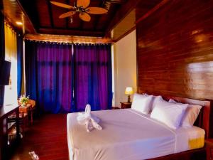 a bedroom with a large white bed with purple curtains at Sengahloune Resort in Ban Khon