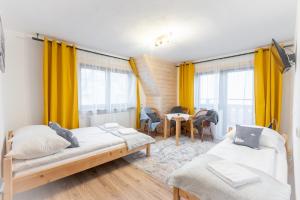 a bedroom with two beds and a dining room with yellow curtains at U Stosela- wiejski dom w górach in Biały Dunajec