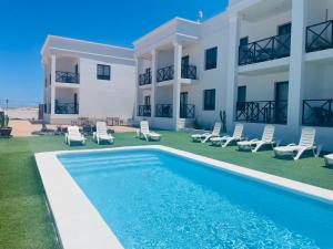 a villa with a swimming pool in front of a building at Sunset Dream Suite El Cotillo in El Cotillo