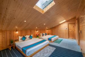two beds in a wooden room with a skylight at Khwaab Stays in Shoja +2 photos