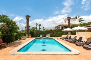 a swimming pool with chairs and a house at Villa Varadero by Escape Home in Alaior