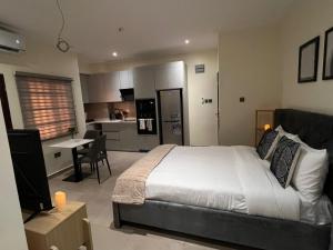 a bedroom with a large bed and a kitchen at Veron, Dzorwulu in Accra +7 photos