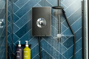 a shower in a blue tiled bathroom at Station Suites Aparthotel in Middlesbrough