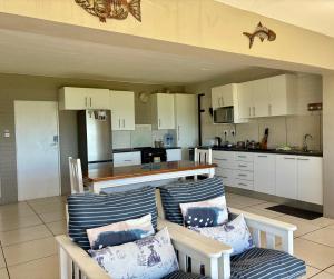 a kitchen with two chairs and a kitchen with white cabinets at Godolphin beach house in Cape St Francis