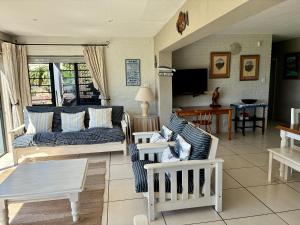 a living room with a couch and chairs and a tv at Godolphin beach house in Cape St Francis