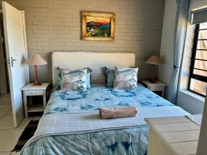 a bedroom with a large bed with blue sheets and pillows at Godolphin beach house in Cape St Francis