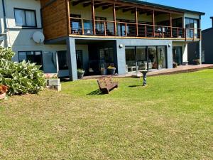 a building with a bench in the grass in front of it at Godolphin beach house in Cape St Francis