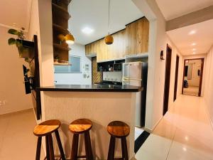 a kitchen with three bar stools and a counter top at Casa Spar do Atlântico com Piscina in Maricá +34 photos
