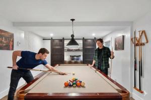 two men playing pool in a room with a pool table at Bécassines Private Spa & Pool table , Waterfront in Nominingue