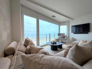 a living room with a couch and a large window at NEPTUNE Wenduine met zeezicht - VOSPROPERTIES in Wenduine