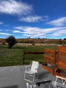 a white chair and a wooden fence and a field at cabaña Quovadis in Trevelín