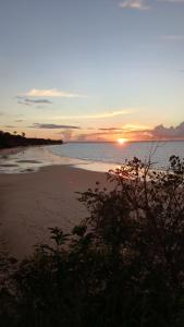 a beach with the sun setting in the distance at Choupana Siriá in Belém