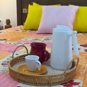 a tray with two cups and a pitcher on a bed at Casa amarela Recanto Doce Lar in Gravatá