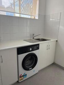 a washing machine in a kitchen next to a sink at The Studio on Barberry with a Pool in Perth