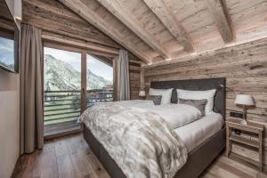 a bedroom with a large bed and a large window at Aadla Walser-Chalets mit privater Sauna, Hotpot und Hotelservice in Schröcken