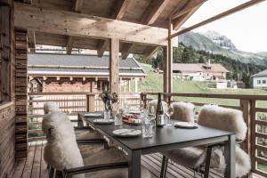 a dining table on a deck with a view of a mountain at Aadla Walser-Chalets mit privater Sauna, Hotpot und Hotelservice in Schröcken +27 photos