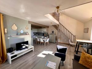 a living room with a couch and a tv and a staircase at Le Champlain Duplex Port de plaisance in Dieppe
