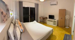 a bedroom with a white bed and a television at The Summer Cottage Koh Chang in Khlaung Phai Bae