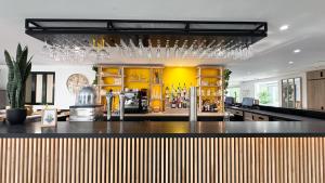 a kitchen with a bar with glasses hanging above it at Campanile Tours Sud - Chambray-Les-Tours in Chambray-lès-Tours