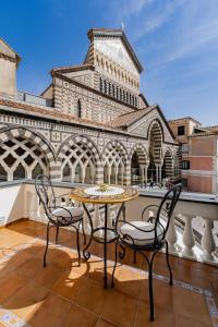 a table and two chairs on a balcony with a clock tower at La Suite Del Cavaliere in Amalfi