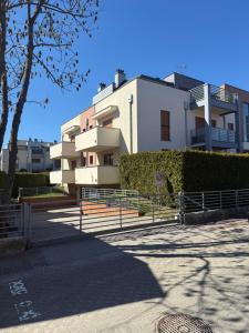 a white building with a fence in front of it at Apartament Gardenia Sun in Międzywodzie