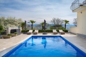 a swimming pool with lounge chairs and a house at Apartment Paradiso - Ravni in Labin