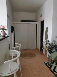a living room with two white chairs and a door at Appartement T2 centre-ville in Corte