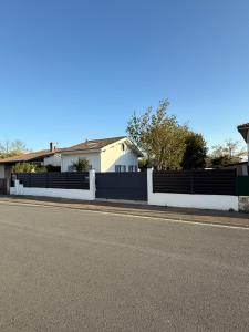 a fence on the side of a road next to a house at Maison individuelle Hourtin centre jardin clos in Hourtin +3 photos