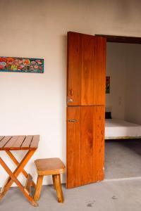 a room with a wooden door and a stool and a bed at Pousada Vila Mundi Itaúnas in Itaúnas