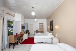 a bedroom with two beds and a table and a desk at Hotel SPA Paraíso in Cruzeiro do Sul