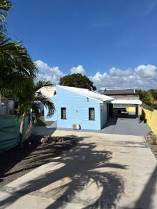a white building with a palm tree in front of it at Villa Coeur Bleu in Petit-Bourg