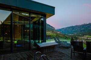 a house with a deck with chairs and a table at La Roccia Wellness Hotel in Cavalese +85 photos