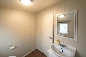 a white bathroom with a sink and a mirror at Prime lakeside caravan at Haven Golden Sands in Mablethorpe