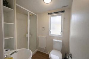 a bathroom with a toilet and a sink and a window at Prime lakeside caravan at Haven Golden Sands in Mablethorpe