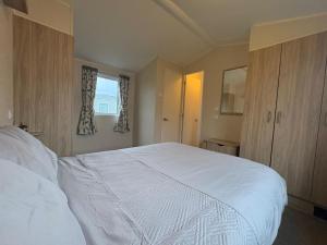 a bedroom with a large white bed and a window at Prime lakeside caravan at Haven Golden Sands in Mablethorpe +19 photos
